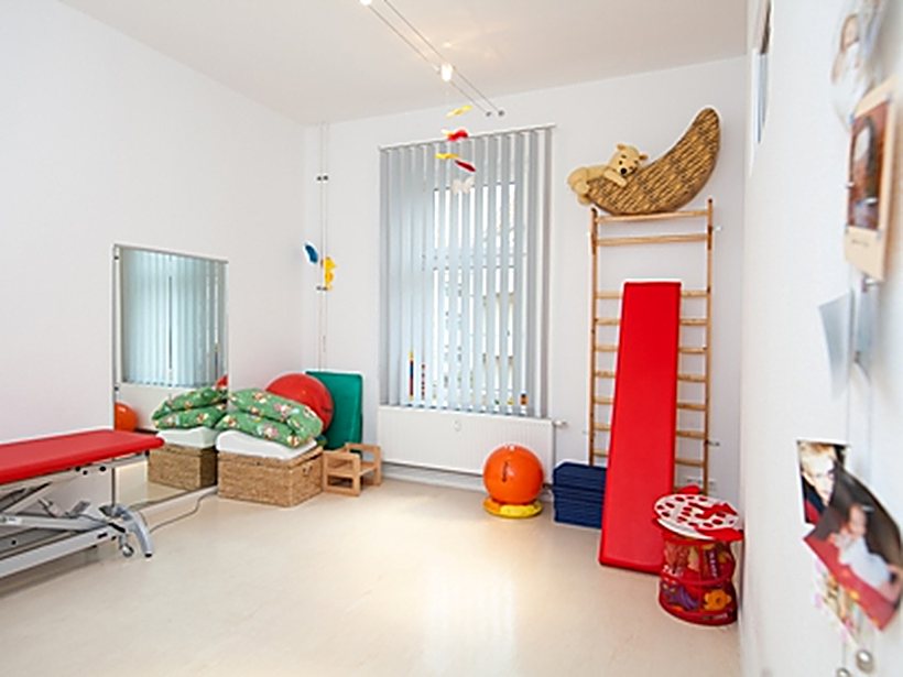 Heller Behandlungsraum mit Therapieliege und Sprossenwand